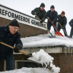 Vrijwilligers ruimen sneeuw Barneveldse kerkdak